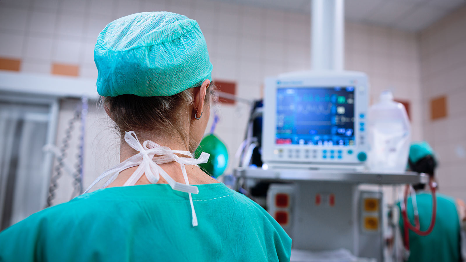 Female anesthesiologist with vital functions monitor in surgery room